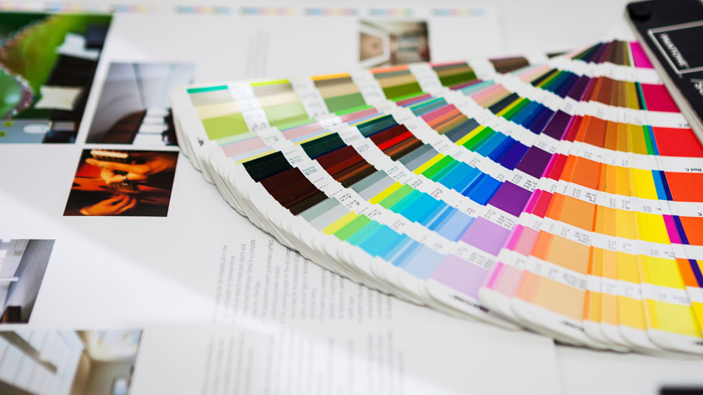 Designer préparant fichier impression sur logiciel PAO avec nuancier couleurs