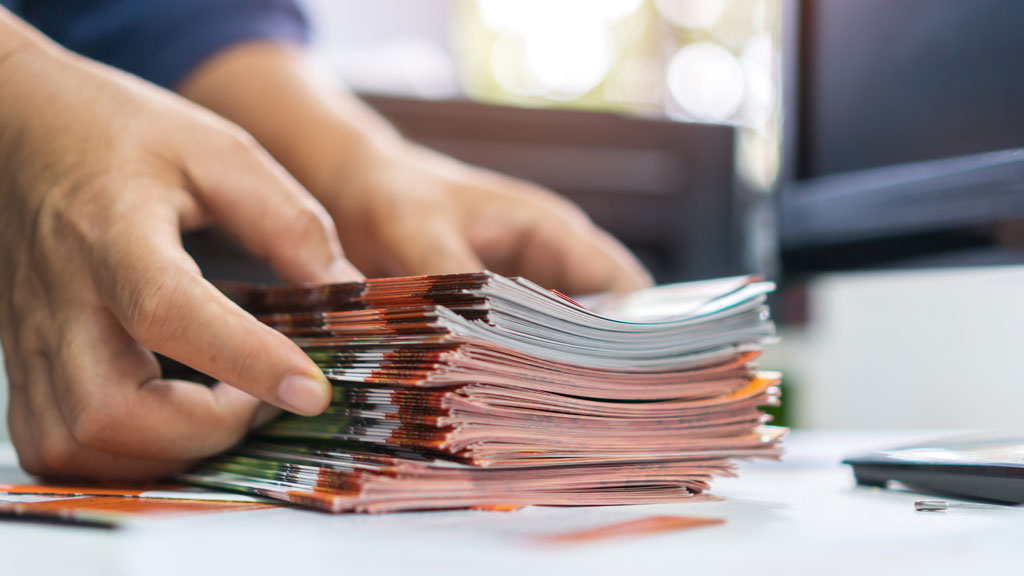 Collaborateur déballant carton de flyers imprimés dans hall d'entreprise